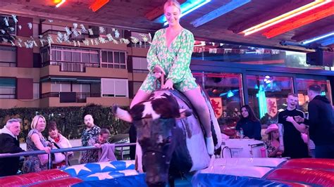 Brunette Girl in White Skirt Riding on a Bull in Benidorm 